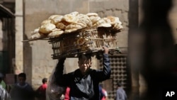 FILE - An Egyptian bread vendor looks for clients on el-Moez Street in historic Fatimid Cairo, March 12, 2015.