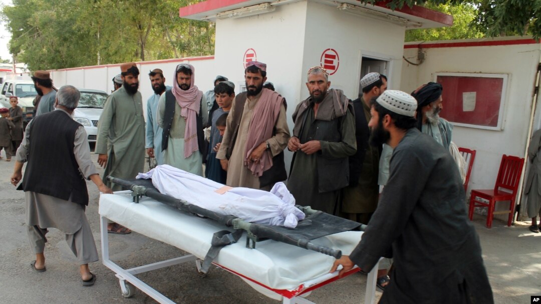 Afghans carry the body of a man who was killed during an attack, in the southern Helmand province, June 29, 2020. 