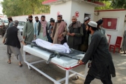 Afghans carry the body of a man who was killed during an attack, in the southern Helmand province, June 29, 2020.