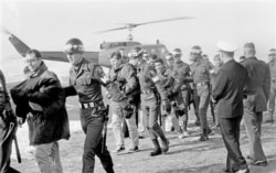 FILE - Released crewmen of the USS Pueblo are escorted by MPs upon their arrival at the U.S. Army 121st Evacuation Hospital at Ascom City, 10 miles west of Seoul, Dec. 23, 1968.