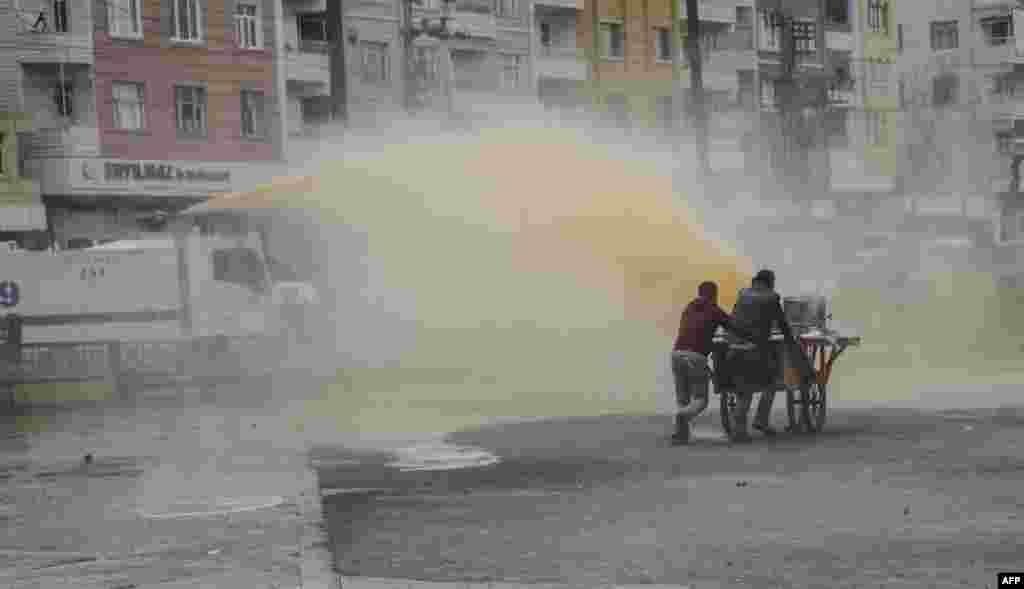 Two men with a tea wagon try to escape from the water cannon used by Turkish police against protesters during a demonstration against government-imposed curfews on areas of eastern Turkey, in Diyarbakir, southeastern Turkey.