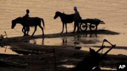 In this photo taken, Saturday, April 3, 2010, Cambodian men take their horses for washing in the Mekong river bank near Khporp village, Kandal province about 22 kilometers (14 miles) north of Phnom Penh, Cambodia.