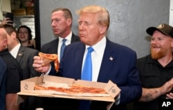 FILE - Former President Donald Trump receiving his order at Downtown House of Pizza in Downtown Fort Myers, takes a moment to enjoy his slice after speaking at the Lee County Republican dinner in Fort Myers, Fla., Friday, April 21, 2023. (AP Photo/Chris Tilley)