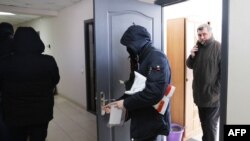 Фото: голова Білоруської Асоціації журналістів Андрій Бастунець та білоруський поліцейський під час обшуку 16 лютого, Мінськ