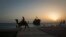 A man rides his camel along the coast, in front of the beached Greek ship Moula F, during sunset off Kish Island, 1,250 km (777 miles) south of Tehran, April 27, 2011. 