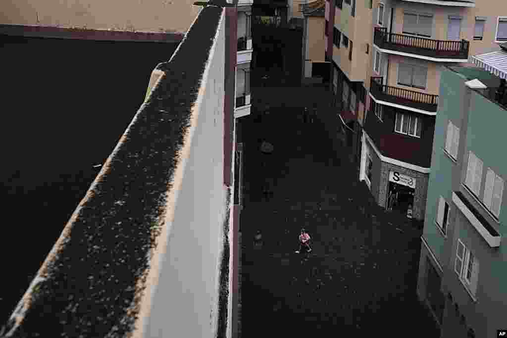 A woman walks down a street that is covered in ash from the volcano in Santa Cruz de la Palma on the Canary island of La Palma, Spain, Sept. 26, 2021.