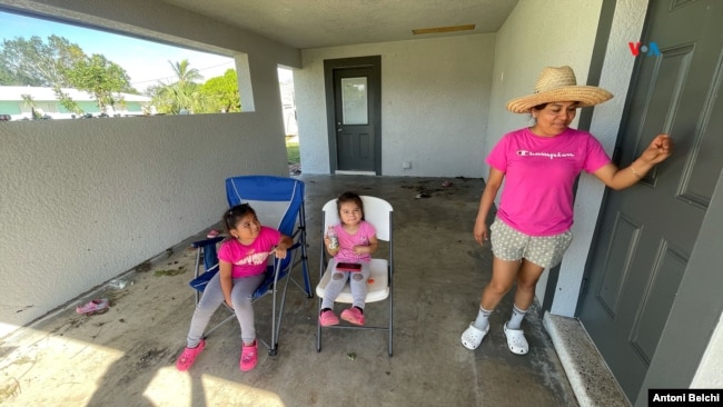 Elizabeth junto a sus dos hijas en el portal de su casa en Fort Myers, Florida, horas después del paso del huracán Milton. [Foto: Antoni Belchi/VOA]