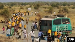 Internally displaced people carry water from outside as they walk toward the entrance of a United Nations Mission in the Republic of South Sudan base in Malakal, Feb. 6, 2014.