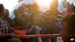 Palestinians evacuate a wounded woman during a protest on the beach at the border with Israel near Beit Lahiya, northern Gaza Strip, Monday, Oct. 8, 2018.