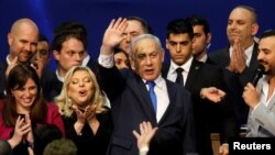 Israeli Prime Minister Benjamin Netanyahu stands next to his wife, Sara, as he waves to supporters following the announcement of exit polls in Israel's election at his Likud party headquarters in Tel Aviv, Israel, March 3, 2020.