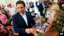 El gobernador de Florida, Ron DeSantis, en el centro, firma un autógrafo durante un evento de recaudación de fondos para la representante estadounidense Ashley Hinson, republicana de Iowa, el 6 de agosto de 2023 en Cedar Rapids, EEUU.