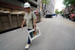 Betsy Williams carries a window she recovered from her apartment in a building damaged in a Dec. 25, 2020, suicide bombing, June 25, 2021, in Nashville, Tenn.