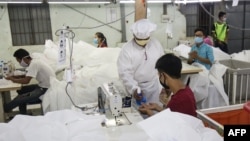 This photo taken on May 8, 2020 shows workers wearing face masks sewing disposable surgical gowns for health workers as protection from the COVID-19 coronavirus at a garment factory in Yangon. - The factory which has switched from making clothes for expor