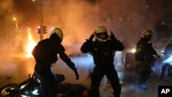 Un policía yace herido en la calle mientras sus colegas reaccionan durante enfrentamientos en Atenas, el martes 9 de marzo de 2021.