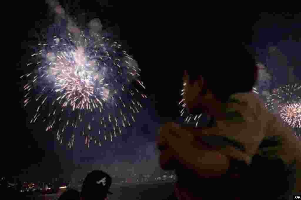 Spectators watch the annual Independence Day fireworks over the Hudson River, Monday, July 4, 2011, in New York. A portion Manhattan's west side is closed to vehicular traffic, allowing pedestrians to camp out and wait for the 40,000 shells launched after