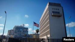 FILE - Tourists in a vintage car pass by the U.S. Embassy in Havana, Cuba, Nov. 7, 2019.