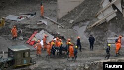 Members of National Disaster Response Force and State Disaster Response Fund carry the body of a victim after recovering it from the debris inside a tunnel during a rescue operation in Tapovan in Uttarakhand state, India, Feb. 14, 2021.