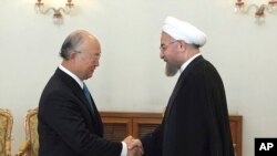 Presiden Iran Hassan Rouhani, kanan, berjabat tangan dengan Kepala Badan Nuklir PBB, Yukiya Amano di Teheran, 17 Agustus 2014. (Foto: dok.)