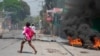 Seorang perempuan yang membawa bayi tampak berlari keluar setelah suara tembakan terdengar di kawasan Port-au-Prince, Haiti, pada 20 Maret 2024. (Foto: AFP/Clarens Siffroy)