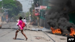 A woman carrying a child runs from the area after gunshots were heard in Port-au-Prince, Haiti, on March 20, 2024.