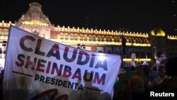 Pessoas seguram uma faixa onde se lê “Presidente Claudia Sheinbaum” depois de o partido Morena, no poder no México, ter declarado Claudia Sheinbaum vencedora das eleições presidenciais, na Praça Zocalo, no centro da Cidade do México, México, a 2 de junho de 2024.