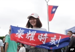 A woman holds a banner reading, "Honor Time," during National Day celebrations in front of the Presidential Building in Taipei, Taiwan, Oct. 10, 2024.