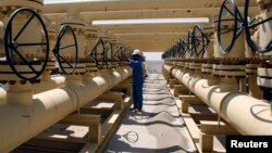 A worker adjusts a pipe at the Nassiriya oilfield in Nassiriya, southeast of Baghdad, Iraq, Sep. 8, 2012. 