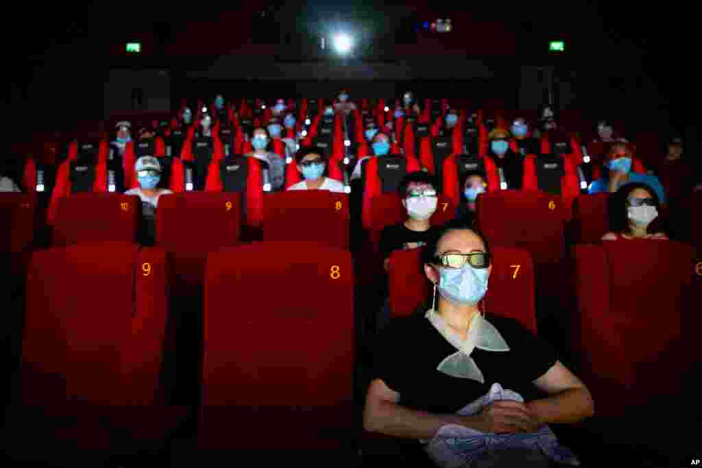 People wearing face masks to protect against the coronavirus sit spaced apart as they watch the film &quot;Dolittle&quot; at a movie theater in Beijing.