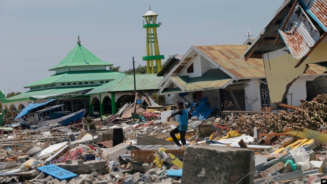 Seorang pria menyelamatkan harga benda dari puing-puing bangunan menyusul tsunami pada pekan lalu yang melanda pemukiman di Donggala, Sulawesi Tengah, 2 Oktober 2018.
