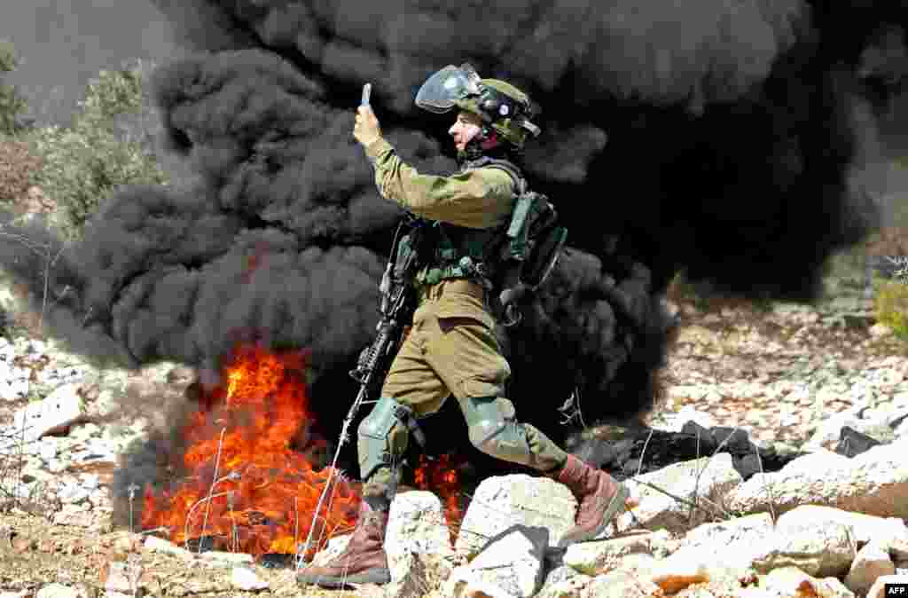 A member of the Israeli security forces takes a photograph with his telephone during clashes with Palestinian protesters after a weekly demonstration in the West Bank village of Kfar Qaddum. (AFP)
