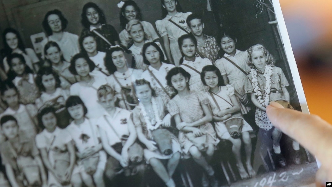 Joan Rodby points to herself in a 1942 photo, in Makawao, Hawaii on Friday, Nov. 18, 2016. After the Pearl Harbor attack, schools required students, including Rodby's childhood friends Emma Veary and Florence Seto, to carry gas masks with them at all times - even when posing for their class photo. 