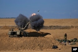 FILE - An Israeli mobile artillery unit fires a shell from southern Israel towards the Gaza Strip, in a position near the Israel-Gaza border, Israel, Sunday, Oct. 15, 2023.