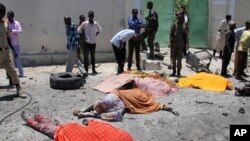 Somalis stand next to the bodies of civilians who were killed in a car bomb attack on a restaurant in Mogadishu, April 5, 2017.