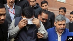 An unidentified member of India's parliament covers his face with a handkerchief after being affected by pepper spray gas in New Delhi, India, Feb. 13, 2014.