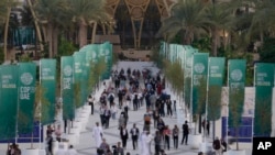 Orang-orang berjalan melalui spanduk KTT Perubahan Iklim PBB COP28, di Dubai, Uni Emirat Arab (4/12). (Foto AP/Peter Dejong)