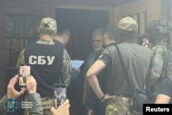 Taipan bisnis Ukraina Ihor Kolomoisky berbicara dengan petugas Dinas Keamanan Ukraina dan Kantor Kejaksaan Agung di lokasi yang tidak diketahui. (Foto: via Reuters)