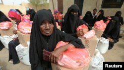 FILE - Women sit next to food aid delivered by the International Committee of the Red Cross to internally displaced people in the Red Sea port city of Hodeida, Yemen, July 21, 2018.