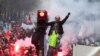 A man stands on a traffic light during a demonstration in Paris, Dec. 5, 2019. Thousands in the capital and elsewhere protested the government's plan to overhaul the retirement system.