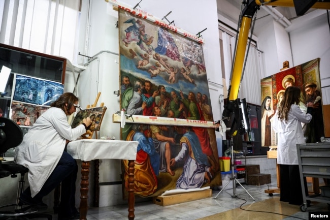 Restorers Chiara Notarsfefano and Caterina Manisco work on paintings at the "painting and wood materials restoration laboratory" inside the Vatican Museums, at the Vatican, December 11, 2023. (REUTERS/Guglielmo Mangiapane)