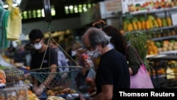 ARCHIVO - Personas compran en un mercado en Caracas, Venezuela. 