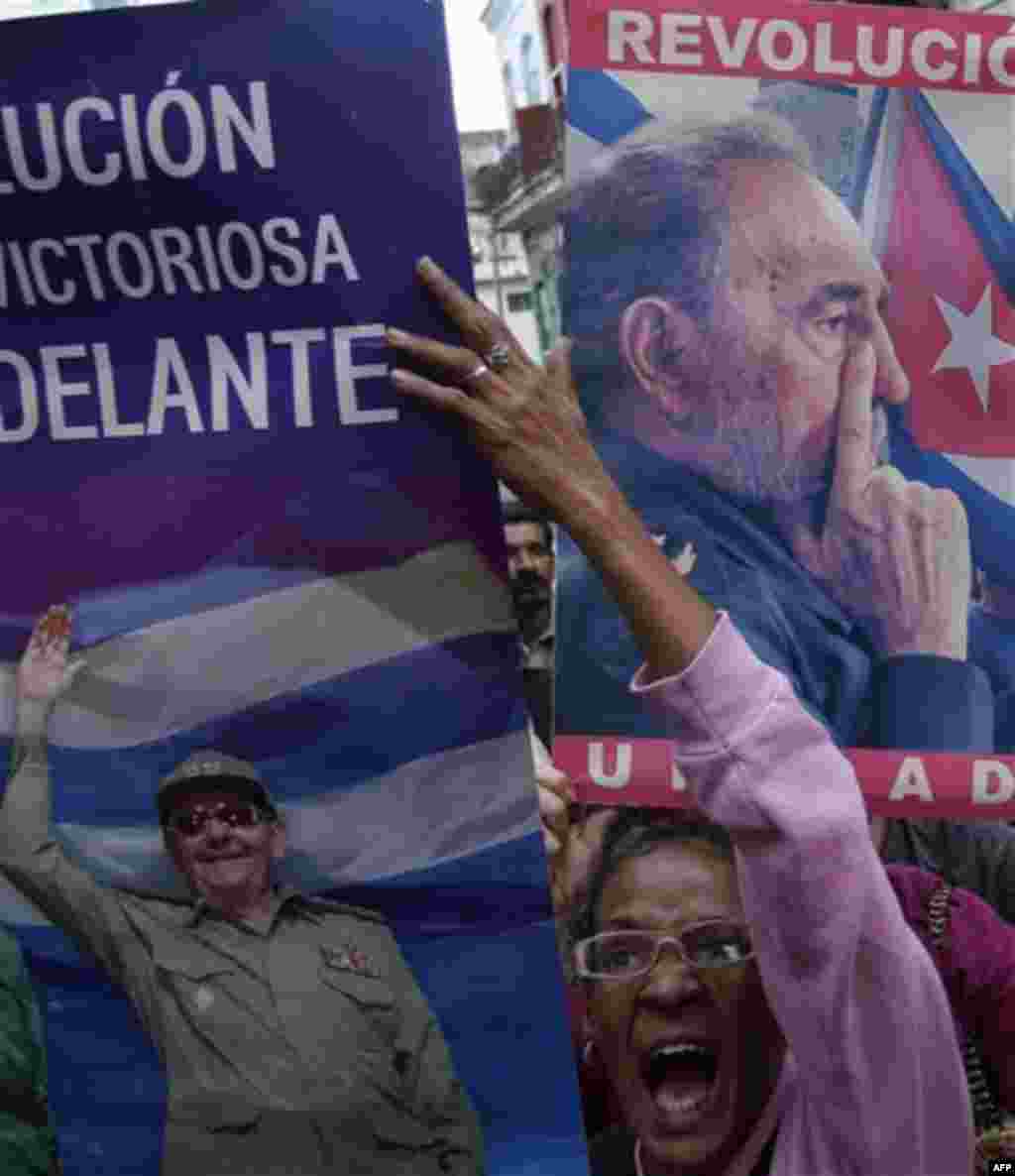 A pro-government demonstrator holds up a sign depicting Cuba's President Raul Castro, left, as she chant slogans outside the home of Laura Pollan, the late leader of the Cuban dissident group 'Ladies in White ', in Havana, Cuba, Friday Dec. 9, 2011. Demo
