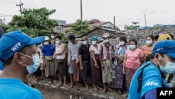 FILE - People wait to receive bags of rice distributed by the World Food Program as part of food aid efforts to support residents living in poor communities on the outskirts of Yangon, Myanmar, May 21, 2021.