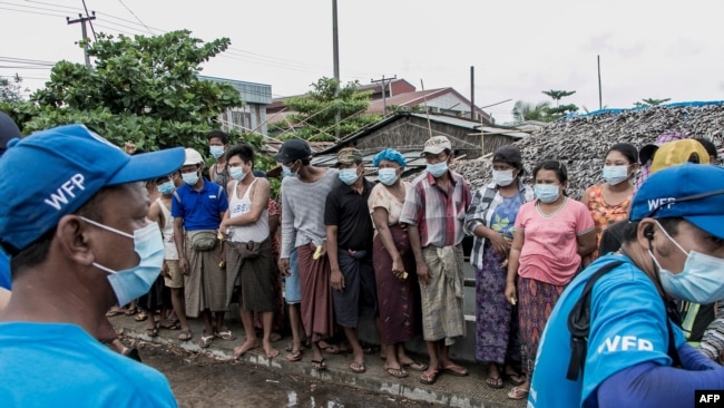 FILE - People wait to receive bags of rice distributed by the World Food Program as part of food aid efforts to support residents living in poor communities on the outskirts of Yangon, Myanmar, May 21, 2021.