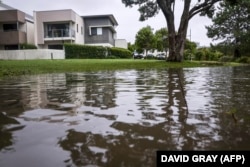 Banjir terlihat di samping rumah-rumah di pinggiran Kota Tugun setelah hujan lebat yang dibawa oleh Siklon Alfred di Gold Coast pada 8 Maret 2025. (Foto: DAVID GRAY/AFP)