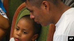 In this image taken from video, Alan Garcia sits next to his 4-year-old son during a news conference in New York, July 11, 2018. The pair were reunited after being separated for almost two months.