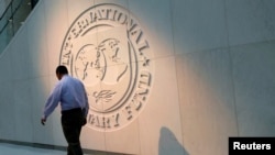 Seorang pria berjalan melewati logo Dana Moneter Internasional (IMF) di kantor pusatnya di Washington, AS, 10 Mei 2018. (Foto: REUTERS/Yuri Gripas)