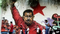 People pass in front a mural depicting Venezuela's President Hugo Chavez in Caracas, Venezuela, February 2, 2011