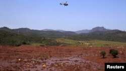 A helicopter flies over the Bento Rodrigues district, covered with mud after a dam owned by Vale SA and BHP Billiton Ltd burst in Mariana, Brazil, Nov. 6, 2015. 