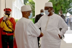 Mali's President Ibrahim Boubacar Keita, right, and Senegal's President Macky Sall exchange greetings outside a Bamako hotel, July 23, 2020. A handful of West African leaders met to discuss Mali's political turmoil over Keita. (K. Traore/VOA)