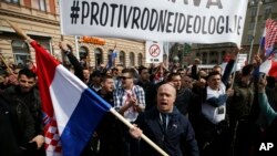 People hold a banner that reads ''Against the gender ideology'' during a protest against an international convention they say indirectly legalizes gay marriages and gives rights to transgender people, in Zagreb, Croatia, March 24, 2018. 